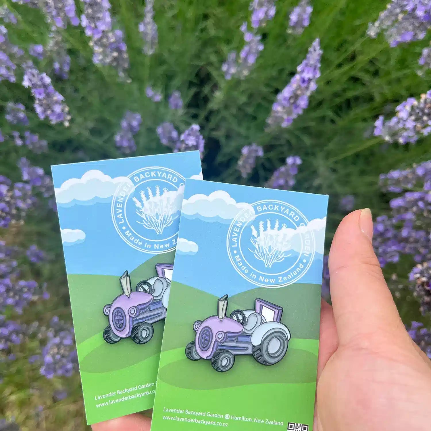 Two purple tractor badges placed among blooming lavender flowers in a serene lavender backyard garden.