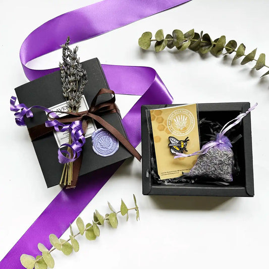 A black gift box featuring a farm-designed badge and lavender sachet, elegantly wrapped with mini dried lavender flowers for a charming touch.